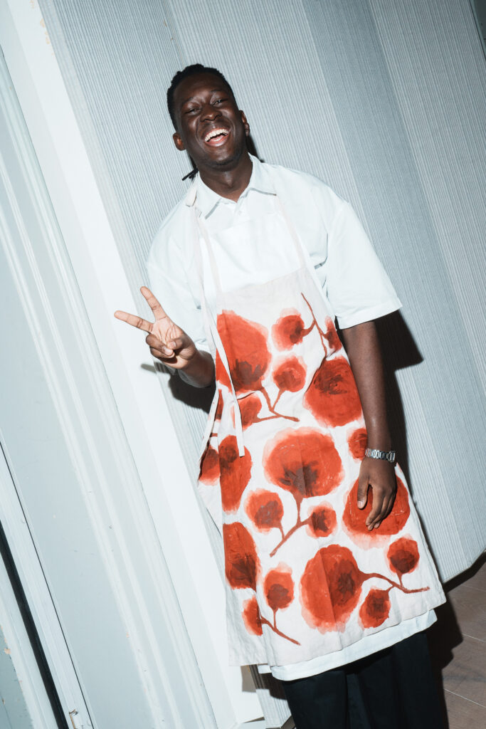 Chef Mory Sacko, guest-curator of See All This #40, wearing one of the hand-painted aprons at See All This' Dinner Party, 6 December 2025 | photo: Katerina Bezede