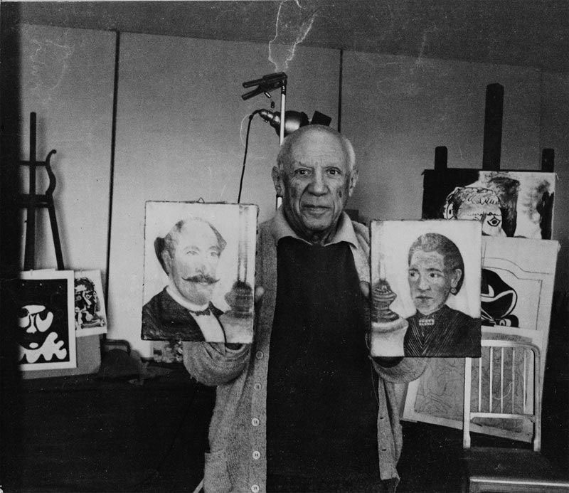 Pablo Picasso holding a self-portrait by Henri Rousseau and a portrait of Rousseau's wife